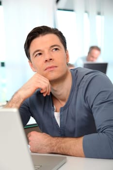 Office worker with exhausted look in front of computer