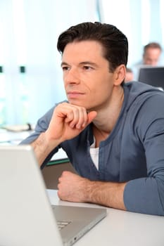 Office worker with exhausted look in front of computer