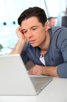 Office worker with exhausted look in front of computer