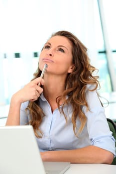Office worker with toughtful look in front of laptop computer