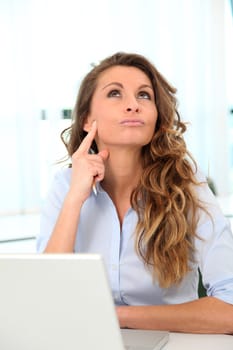 Office worker with toughtful look in front of laptop computer