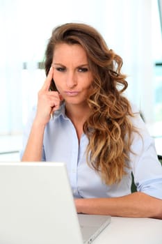 Office worker with toughtful look in front of laptop computer