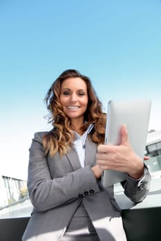 Smiling businesswoman using electronic tablet outside