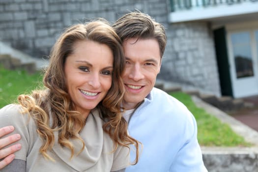 Couple sitting in front of their new home