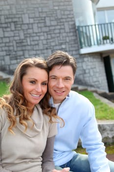 Couple sitting in front of their new home