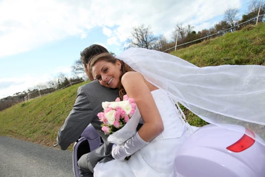 Married couple riding motorcycle on their wedding day