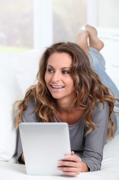 Beautiful woman laying on sofa with electronic tablet