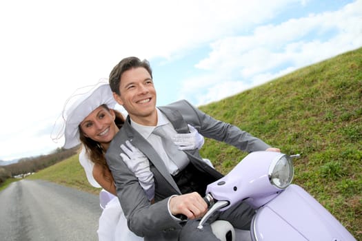 Married couple riding motorcycle on their wedding day