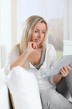 Blond woman using electronic tablet at home