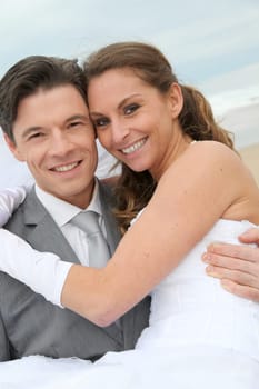 Groom holding bride in his arms at the beach