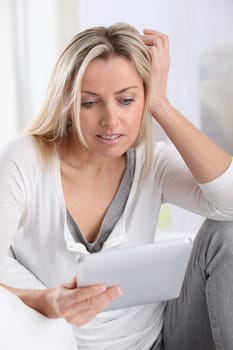Blond woman using electronic tablet at home