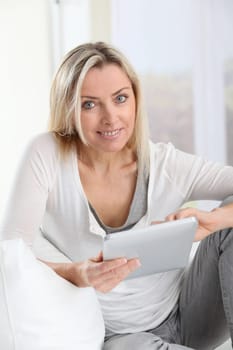Blond woman using electronic tablet at home