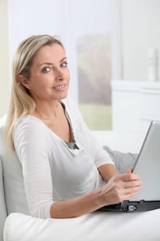 Adult blond woman connected on internet at home