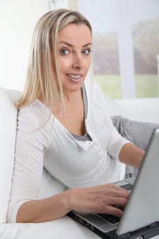 Adult blond woman connected on internet at home