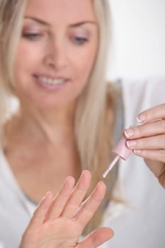 Beautiful blond woman applying nail polish