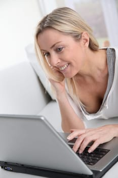 Adult blond woman connected on internet at home