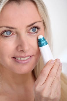 Blond woman applying anti-aging serum on her skin