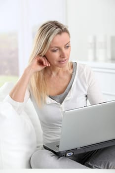 Adult blond woman connected on internet at home