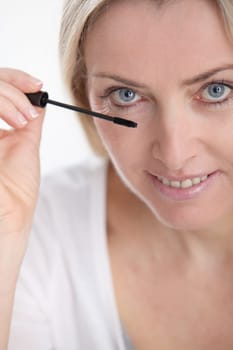 Closeup of woman applying mascara on eyelashes
