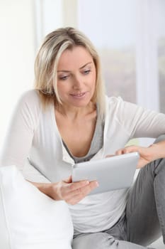 Blond woman using electronic tablet at home