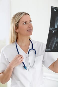 Beautiful blond nurse looking at X-ray