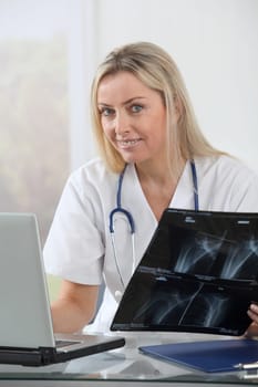 Beautiful blond nurse looking at X-ray