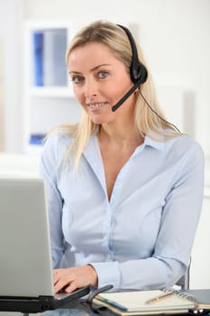 Blond woman in the office with headset on
