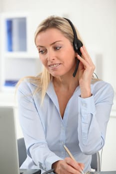 Blond woman in the office with headset on