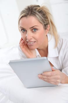 Blond woman using electronic tablet at home