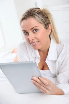 Blond woman using electronic tablet at home