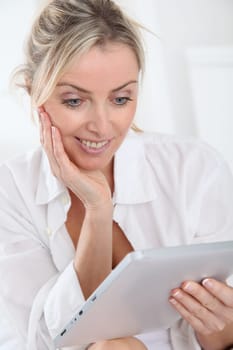 Blond woman using electronic tablet at home