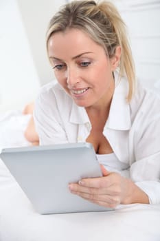 Blond woman using electronic tablet at home