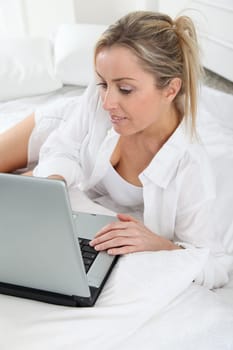Blond woman with laptop computer in bed