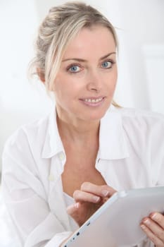 Blond woman using electronic tablet at home