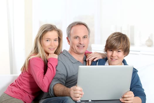 Father and children using laptop computer at home