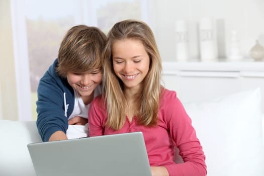 Brother and sister using laptop computer at home