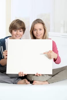 Smiling teenagers sitting in sofa with whiteboard