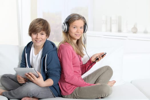 Teenagers sitting in sofa with electronic devices