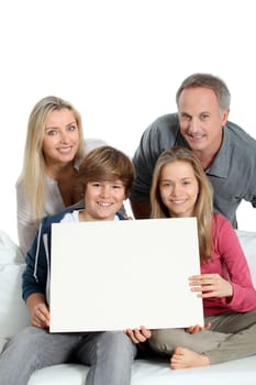 Portrait of happy family holding white message board