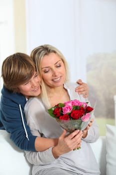 Son offering bunch flowers on mother's birthday
