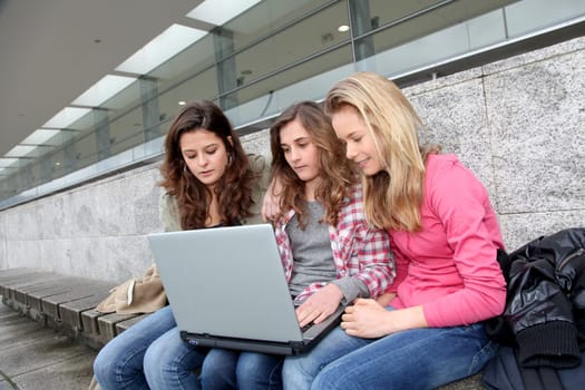 Group of teenage girls with laptop computer in school yard