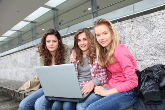 Group of teenage girls with laptop computer in school yard