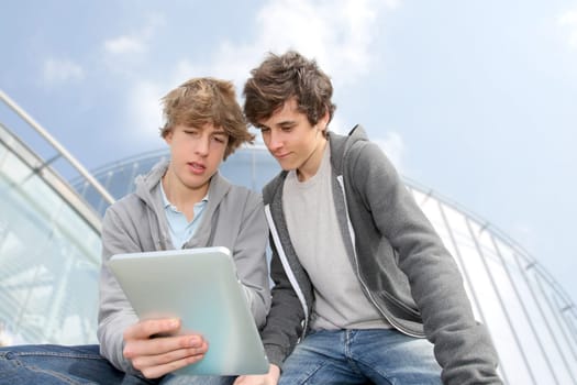 Teenage boys sitting outside with electronic tablet