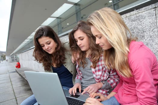 Group of teenage girls with laptop computer in school yard