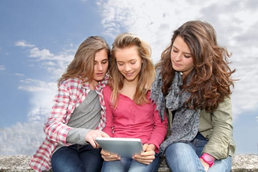 Group of teenage girls with laptop computer in school yard