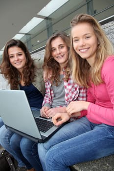 Group of teenage girls with laptop computer in school yard
