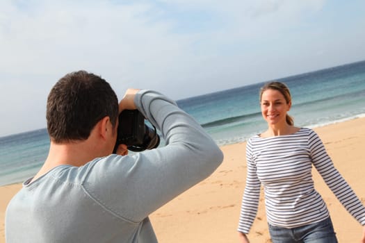Man taking picture of girlfriend at the beach