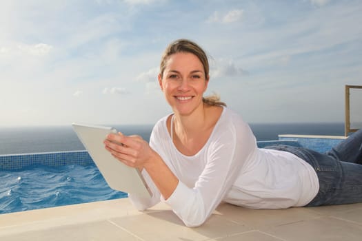 Woman using electronic tablet by swimming pool