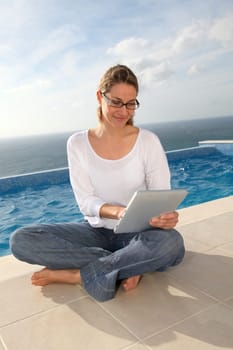 Woman using electronic tablet by swimming pool