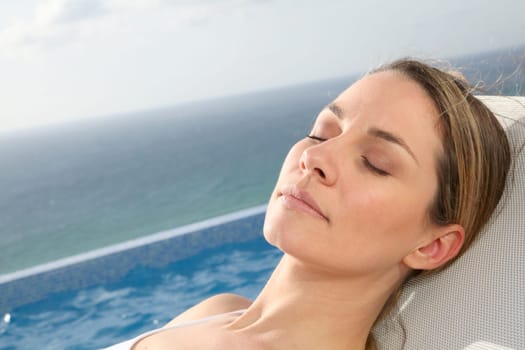 Woman relaxing in deckchair by swimming-pool